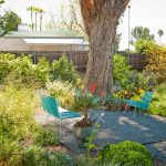 A square patio of gravel is wrapped by lush foliage.