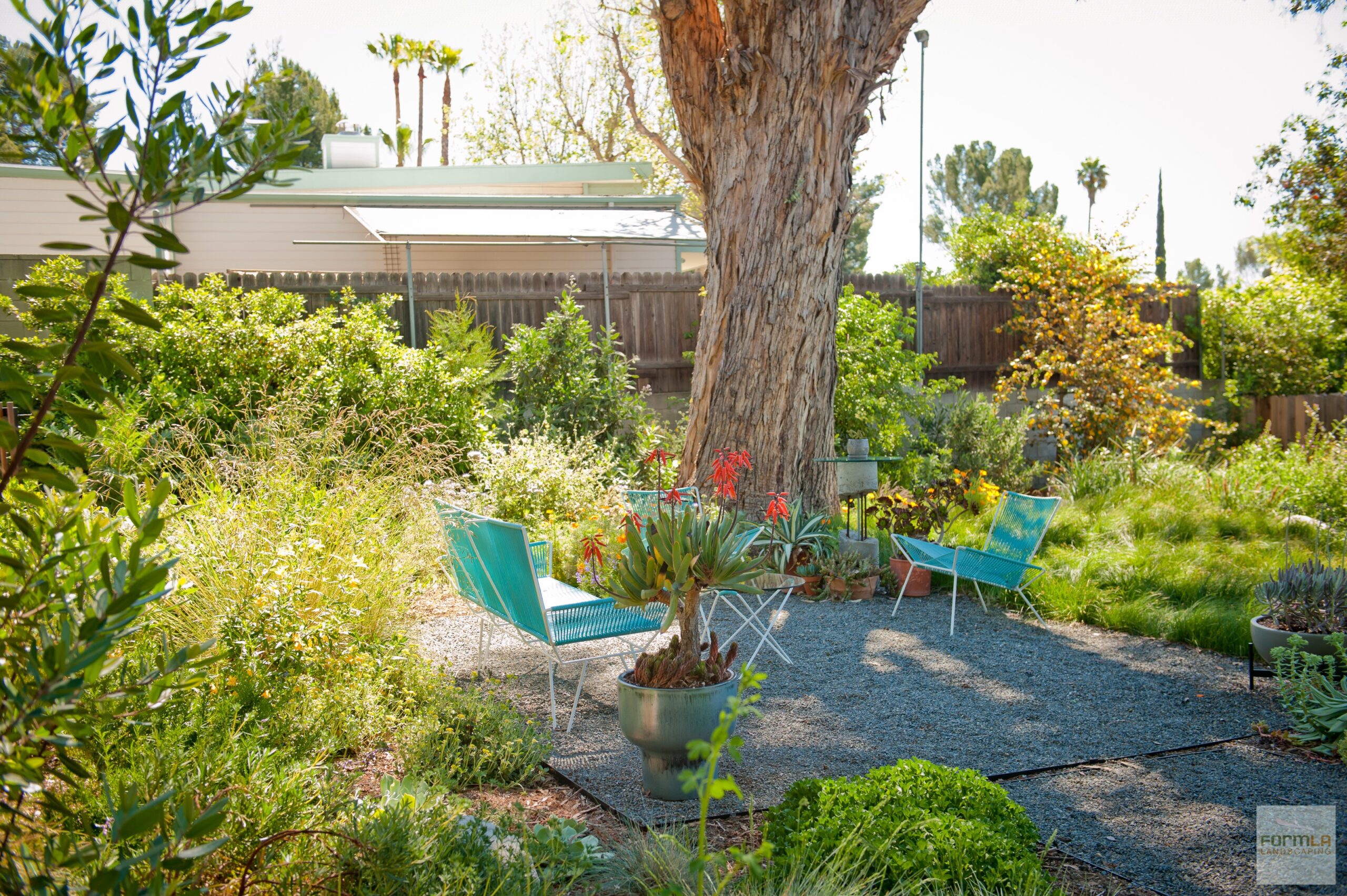 A square patio of gravel is wrapped by lush foliage.